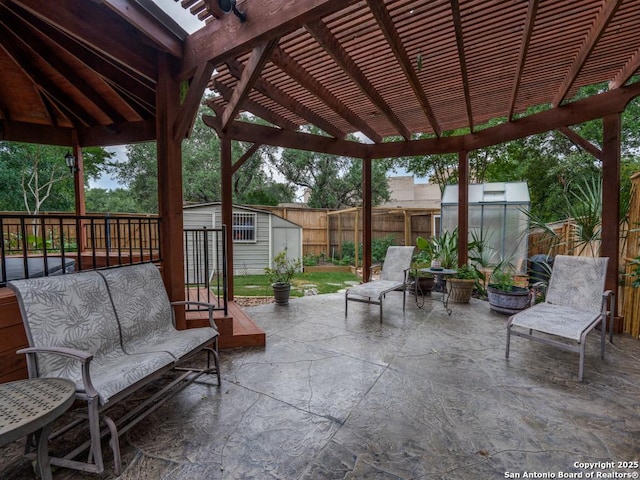 view of patio / terrace featuring a pergola, a fenced backyard, a shed, a greenhouse, and an outbuilding