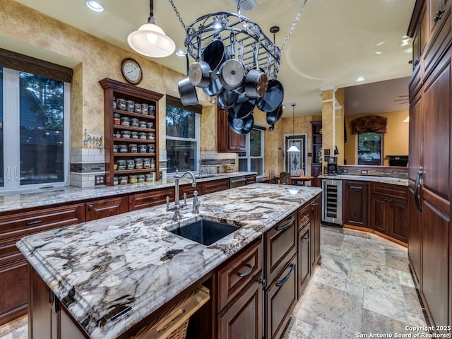 kitchen with stone tile floors, decorative light fixtures, a sink, and wine cooler