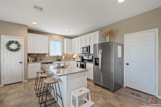 27342 Emilie Cyn, San Antonio, TX 78260 - kitchen with visible vents, a breakfast bar, white cabinets, tasteful backsplash, and stainless steel appliances