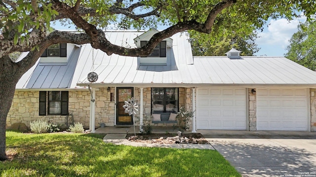 view of front facade with concrete driveway, a standing seam roof, metal roof, and stone siding