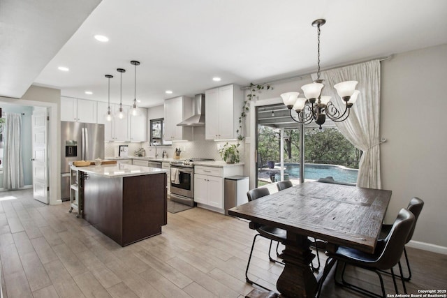 kitchen with wall chimney range hood, stainless steel appliances, a healthy amount of sunlight, and light countertops