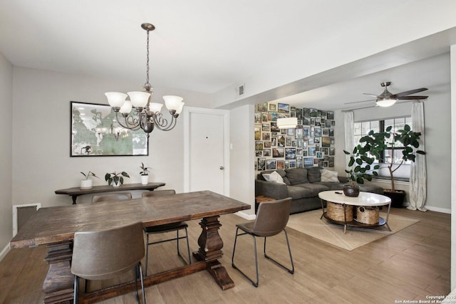 dining area featuring baseboards, visible vents, ceiling fan with notable chandelier, and light wood-type flooring