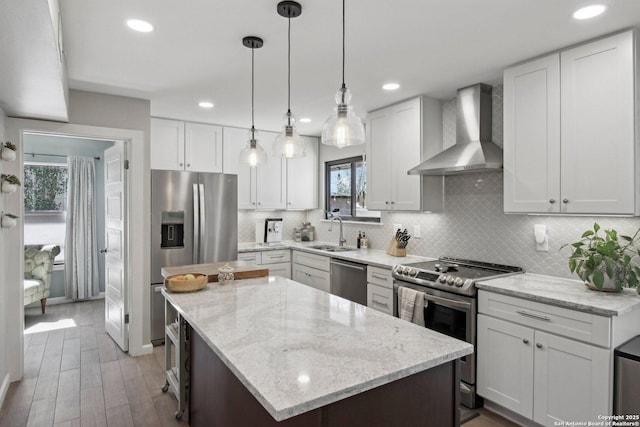 kitchen with appliances with stainless steel finishes, a sink, wall chimney exhaust hood, a center island, and recessed lighting