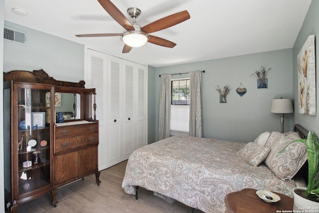 bedroom featuring a ceiling fan, a closet, wood finished floors, and visible vents