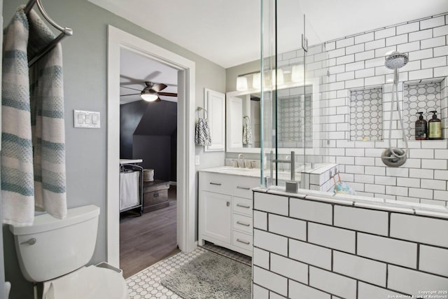 bathroom with a ceiling fan, toilet, a tile shower, and vanity