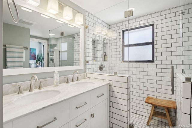 full bathroom with double vanity, tile walls, a shower stall, and a sink