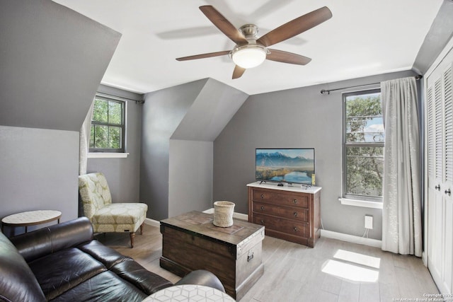 living area featuring light wood-type flooring, a ceiling fan, lofted ceiling, and a healthy amount of sunlight