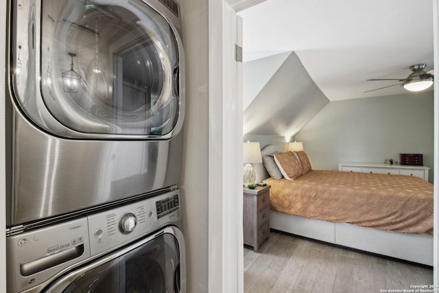 washroom with light wood-type flooring, stacked washer and clothes dryer, a ceiling fan, and laundry area