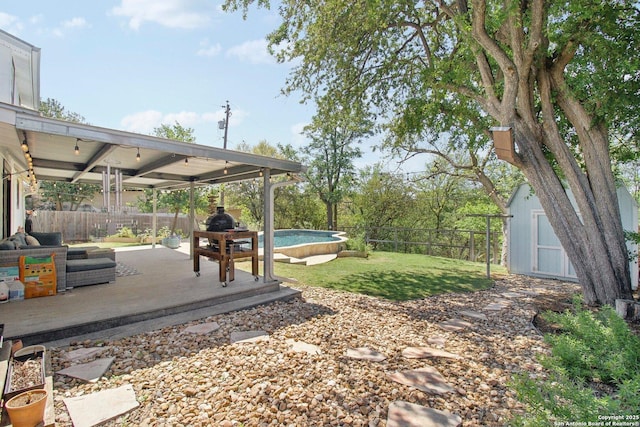 view of yard with a fenced backyard, a shed, a fenced in pool, a patio area, and an outbuilding