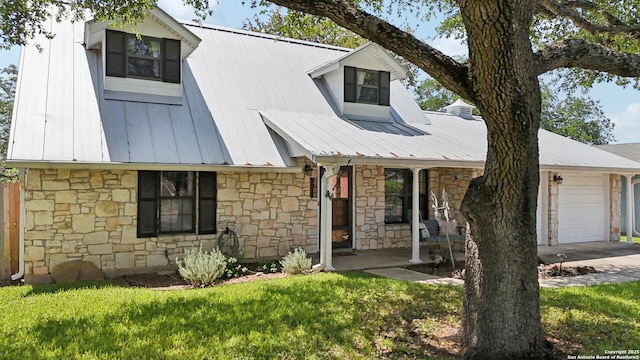 cape cod house featuring a garage, covered porch, stone siding, and metal roof
