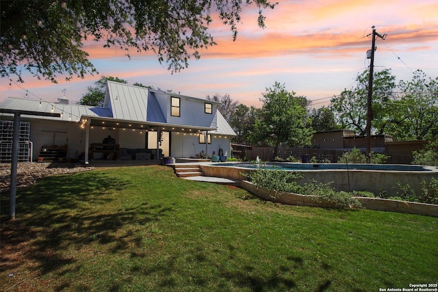 rear view of property featuring a fenced in pool, a standing seam roof, a yard, fence private yard, and metal roof
