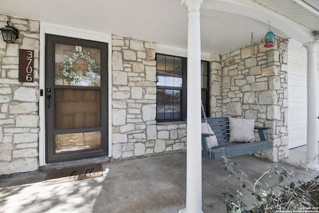 property entrance with covered porch and stone siding