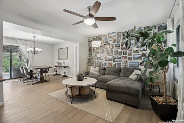 living room featuring baseboards, wood finished floors, and ceiling fan with notable chandelier
