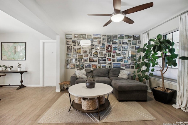 living area with baseboards, ceiling fan, and wood finished floors