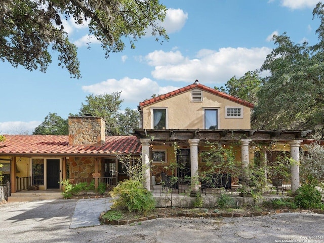 view of front of home with a pergola, covered porch, stucco siding, a chimney, and a tiled roof