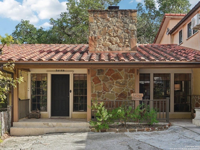 property entrance featuring a tile roof and stone siding