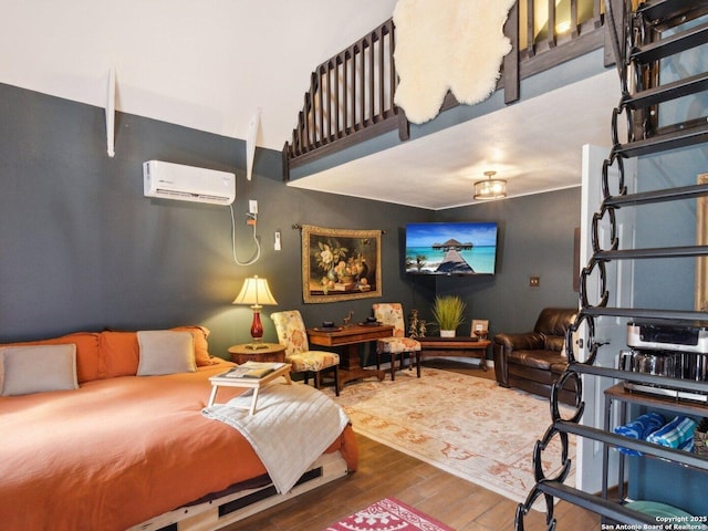 bedroom with wood finished floors and a wall mounted air conditioner