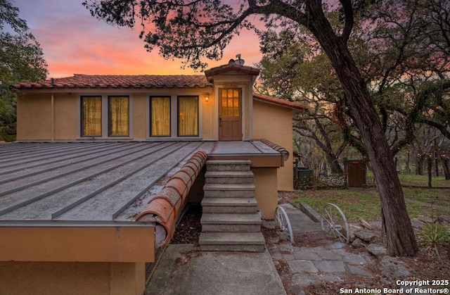 exterior space featuring a standing seam roof, stucco siding, and a tile roof