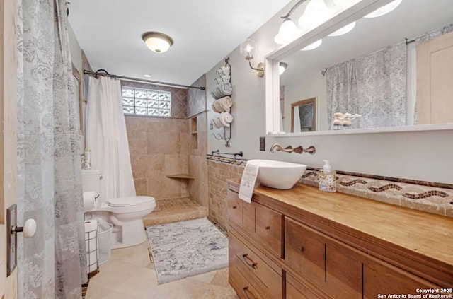 bathroom featuring vanity, a tile shower, and toilet