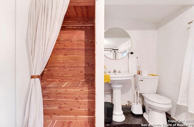 bathroom featuring toilet and a textured wall