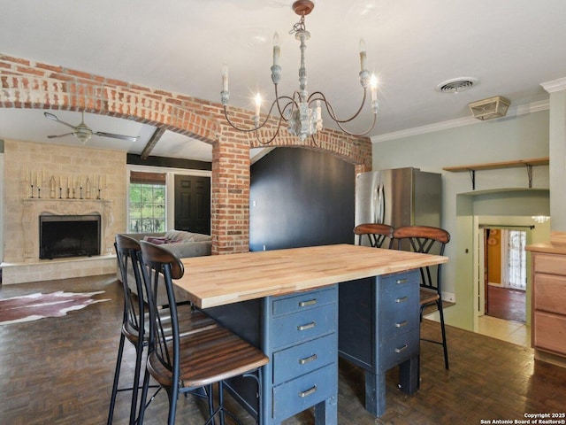 kitchen featuring blue cabinets, ceiling fan with notable chandelier, a kitchen bar, and butcher block countertops