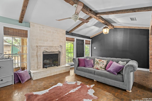 living area with visible vents, lofted ceiling with beams, ceiling fan, and a fireplace
