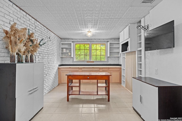 kitchen with an ornate ceiling, open shelves, and brick wall