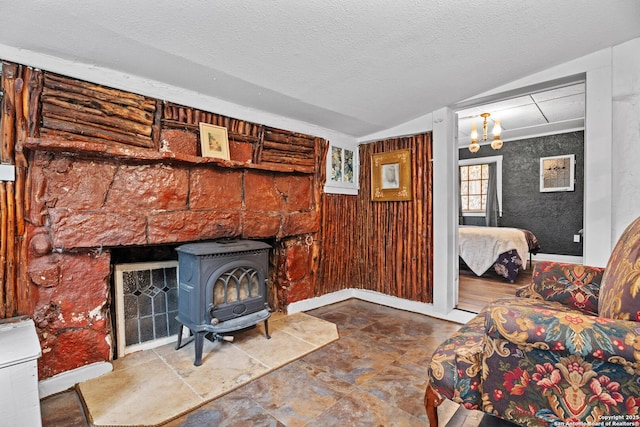 living room featuring a textured ceiling, a wood stove, baseboards, lofted ceiling, and an inviting chandelier