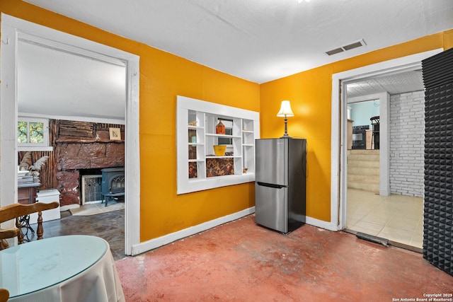 dining area featuring baseboards, a wood stove, concrete floors, and visible vents