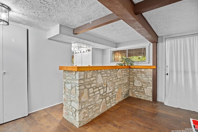 bar with wood-type flooring, a textured ceiling, bar, and beam ceiling
