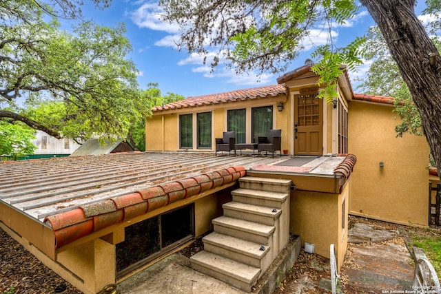 rear view of house with a tile roof and stucco siding