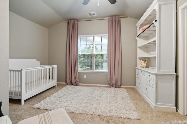 bedroom with a nursery area, visible vents, light carpet, and lofted ceiling