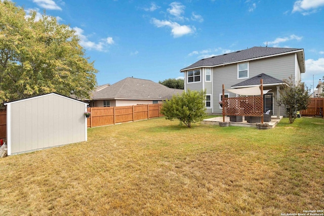 rear view of property featuring a lawn, a patio, an outbuilding, and a fenced backyard
