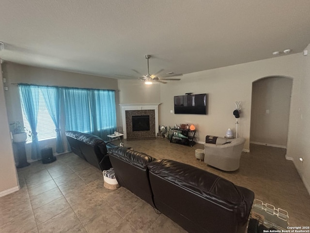 12606 Ozona, San Antonio, TX 78245 - living area with a fireplace, baseboards, ceiling fan, tile patterned floors, and arched walkways
