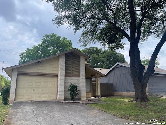 mid-century modern home with an attached garage, aphalt driveway, and brick siding