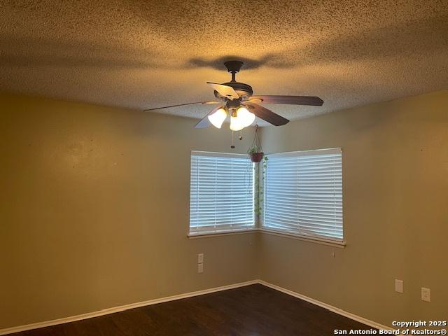 unfurnished room with baseboards, a textured ceiling, ceiling fan, and dark wood-style floors