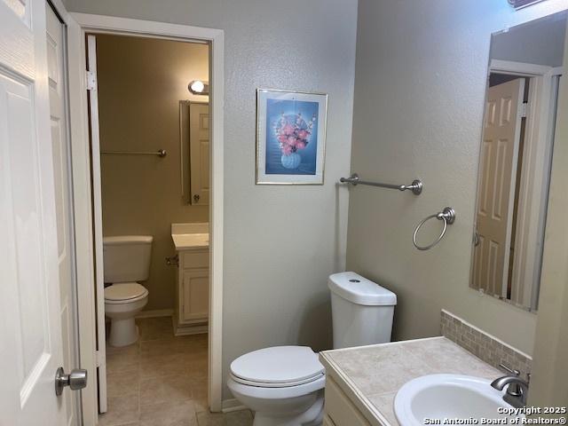 bathroom with toilet, tile patterned floors, baseboards, and vanity