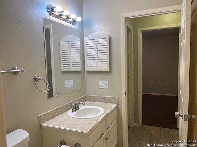 bathroom with toilet, wood finished floors, and vanity