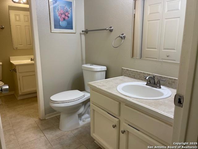 bathroom featuring backsplash, toilet, tile patterned floors, and vanity