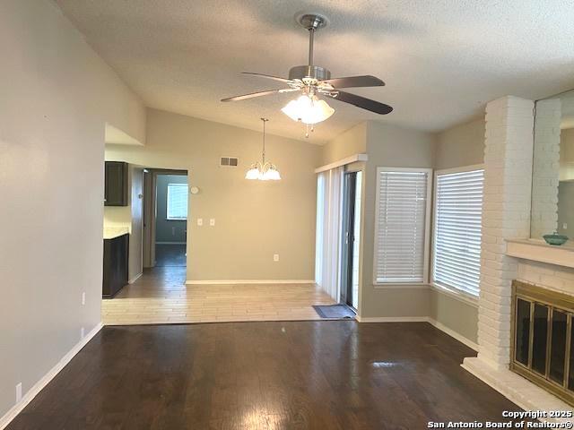 unfurnished living room featuring plenty of natural light, visible vents, ceiling fan with notable chandelier, and lofted ceiling