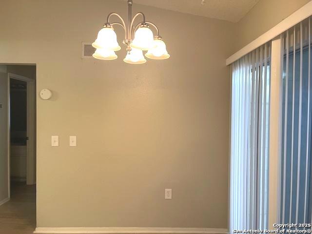 unfurnished room featuring an inviting chandelier, baseboards, and wood finished floors