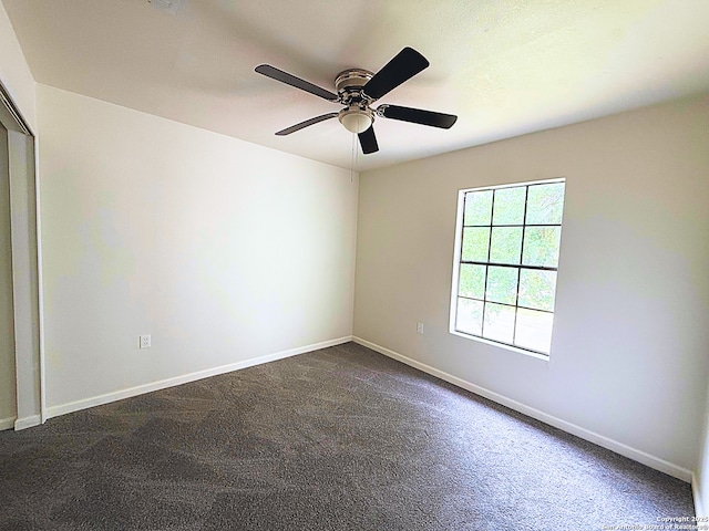 unfurnished room featuring dark carpet, a ceiling fan, and baseboards