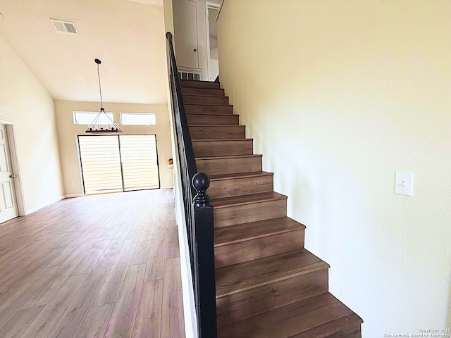 staircase with baseboards, visible vents, and wood finished floors