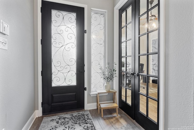 entryway featuring baseboards, a textured wall, and wood finished floors