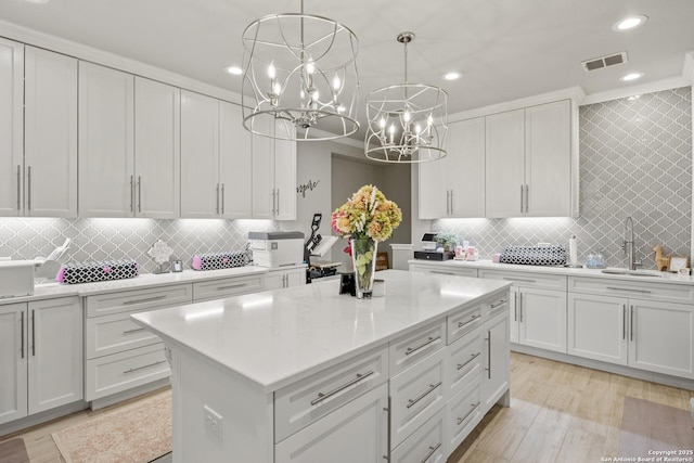 kitchen featuring light countertops, white cabinetry, a notable chandelier, and a sink