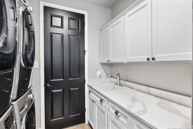 clothes washing area with a sink, cabinet space, and stacked washer / dryer