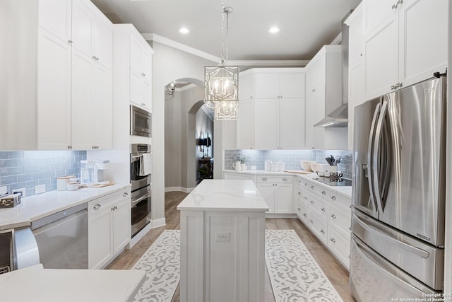 kitchen with pendant lighting, white cabinets, arched walkways, backsplash, and stainless steel appliances