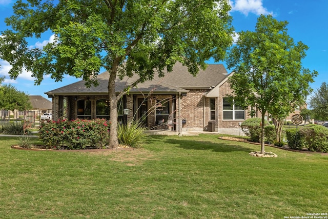 view of front of home featuring brick siding, roof with shingles, and a front lawn