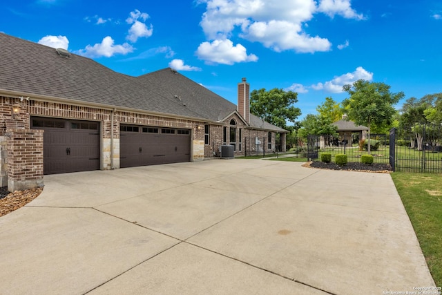 view of home's exterior featuring driveway, a chimney, central AC unit, a garage, and fence