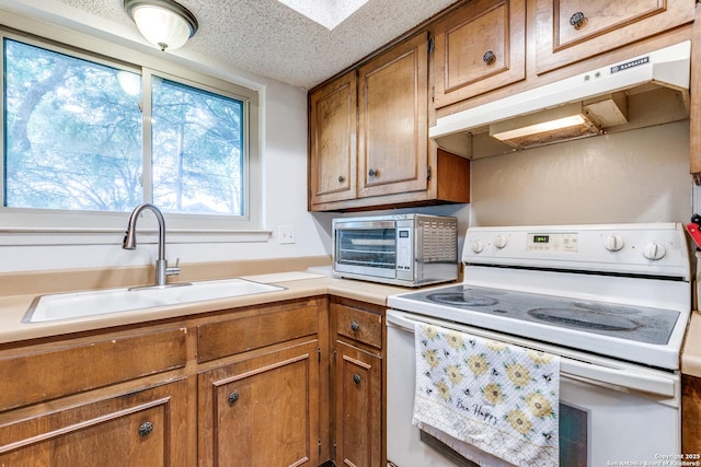 kitchen with electric stove, a sink, under cabinet range hood, and brown cabinets